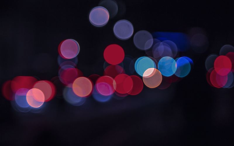 Out-of-focus red, orange, blue and white city lights glowing against the night.